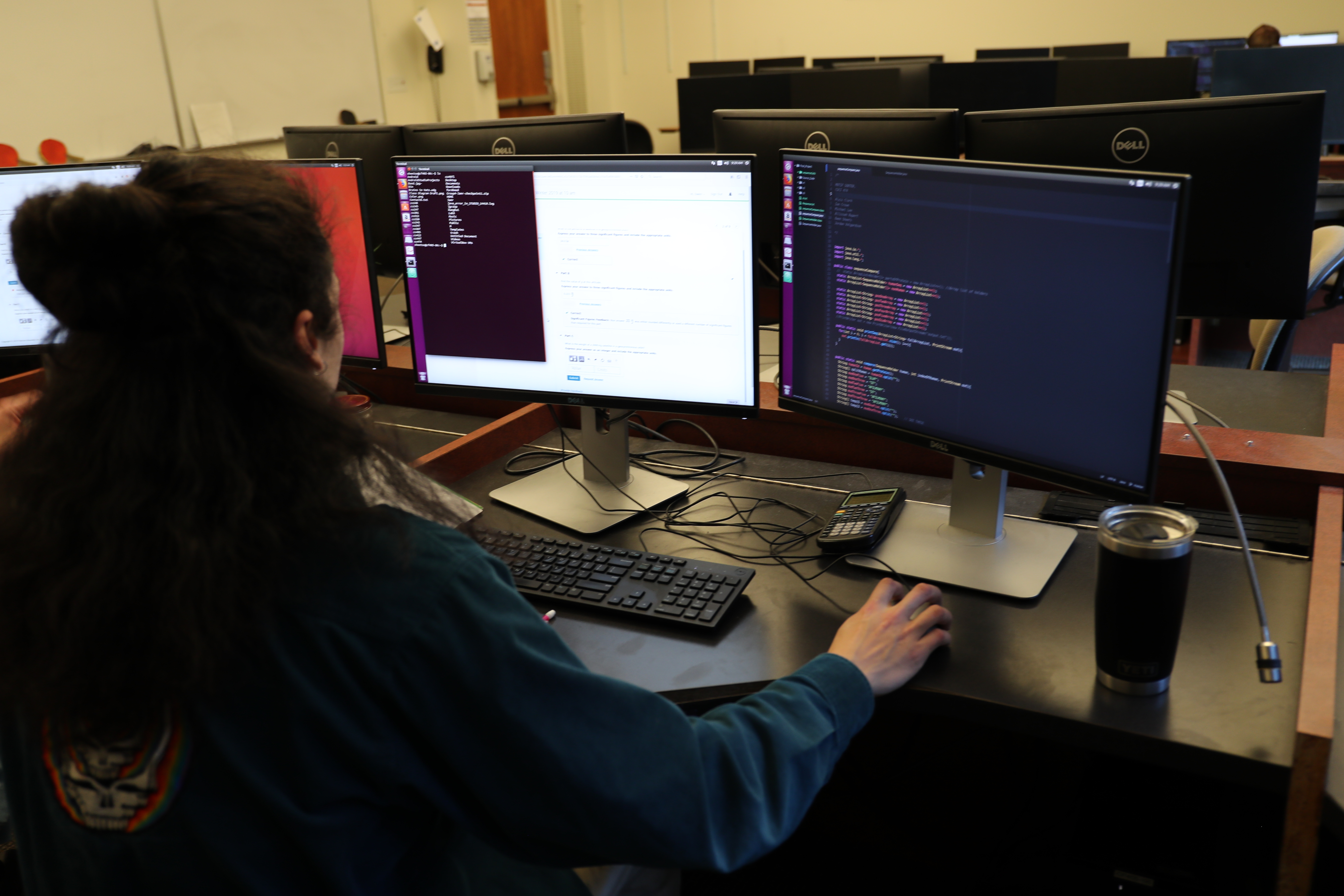 Student coding at two monitor screens